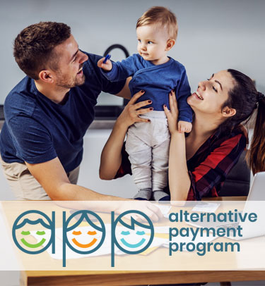 A mother and father play with their toddler son, smiling and laughing.