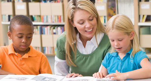 A caregiver reads with two children.