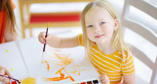 A young child is painting with watercolor.