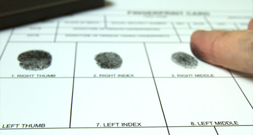 A photo of paper with black ink fingerprints.